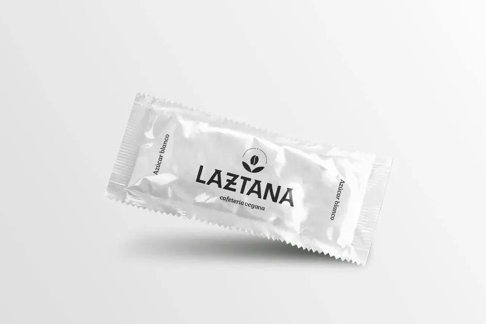 Sobre de azúcar blanco con el logotipo de una cafetería vegana en Bilbao en negro.