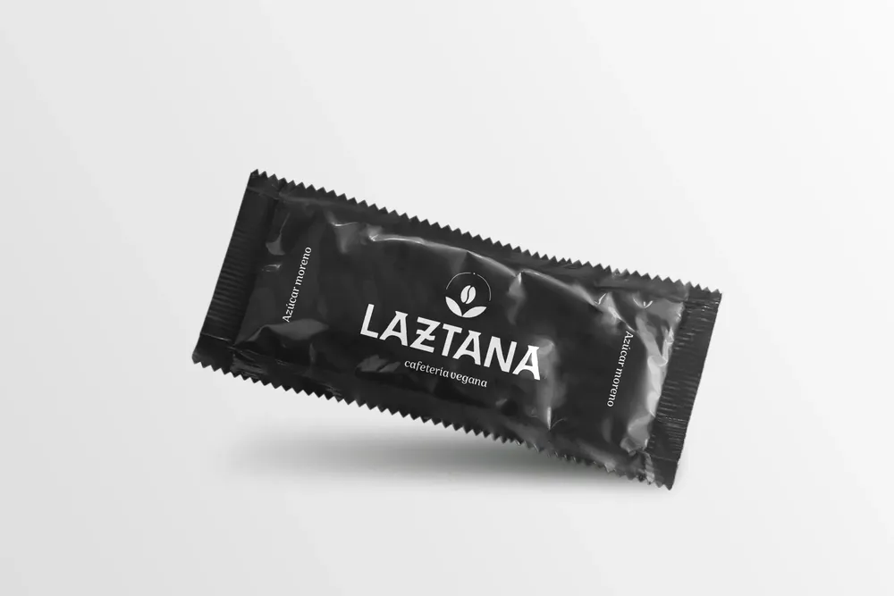 Sobre de azúcar negro con el logotipo de una cafetería vegana en Bilbao en blanco.