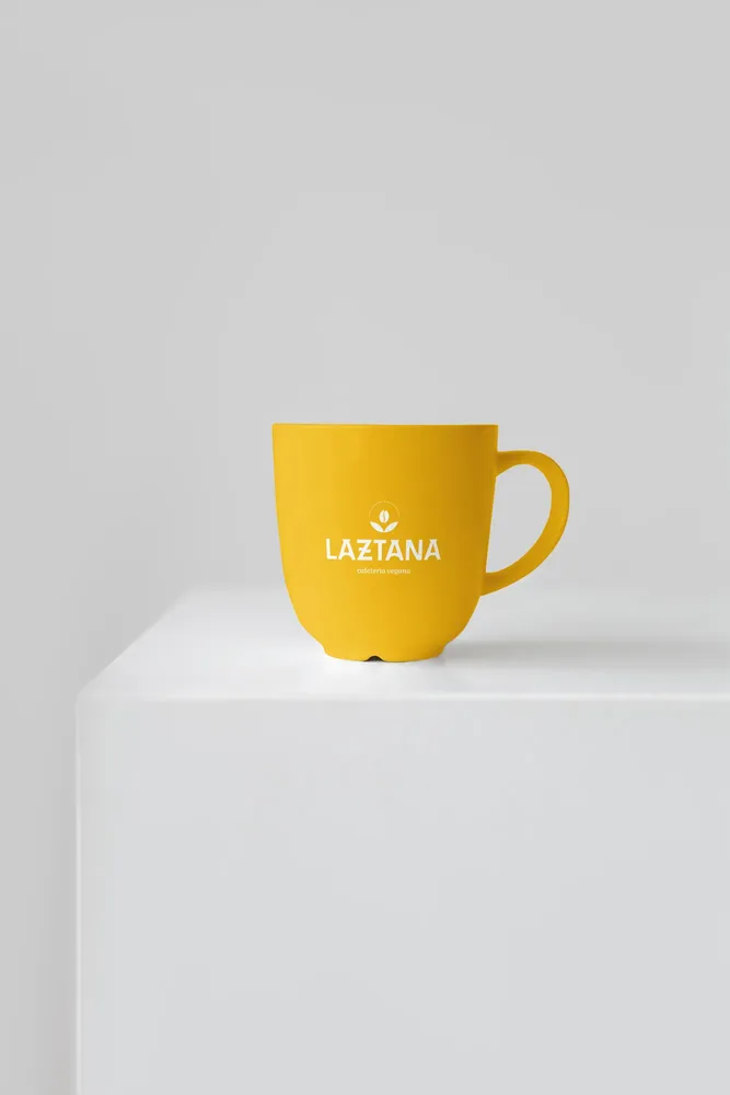 Taza amarilla con el logo de la cafetería vegana Laztana en Bilbao.