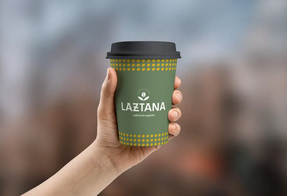 Vaso sujetado por una mano con el logo de una marca en de cafeteria vegana en Bilbao.